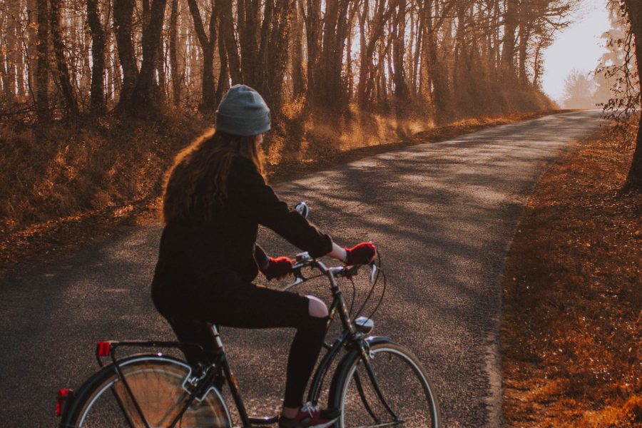 Frau sitzt auf einem Fahrrad. Im Hintergrund sieht man eine Herbstlandschaft.